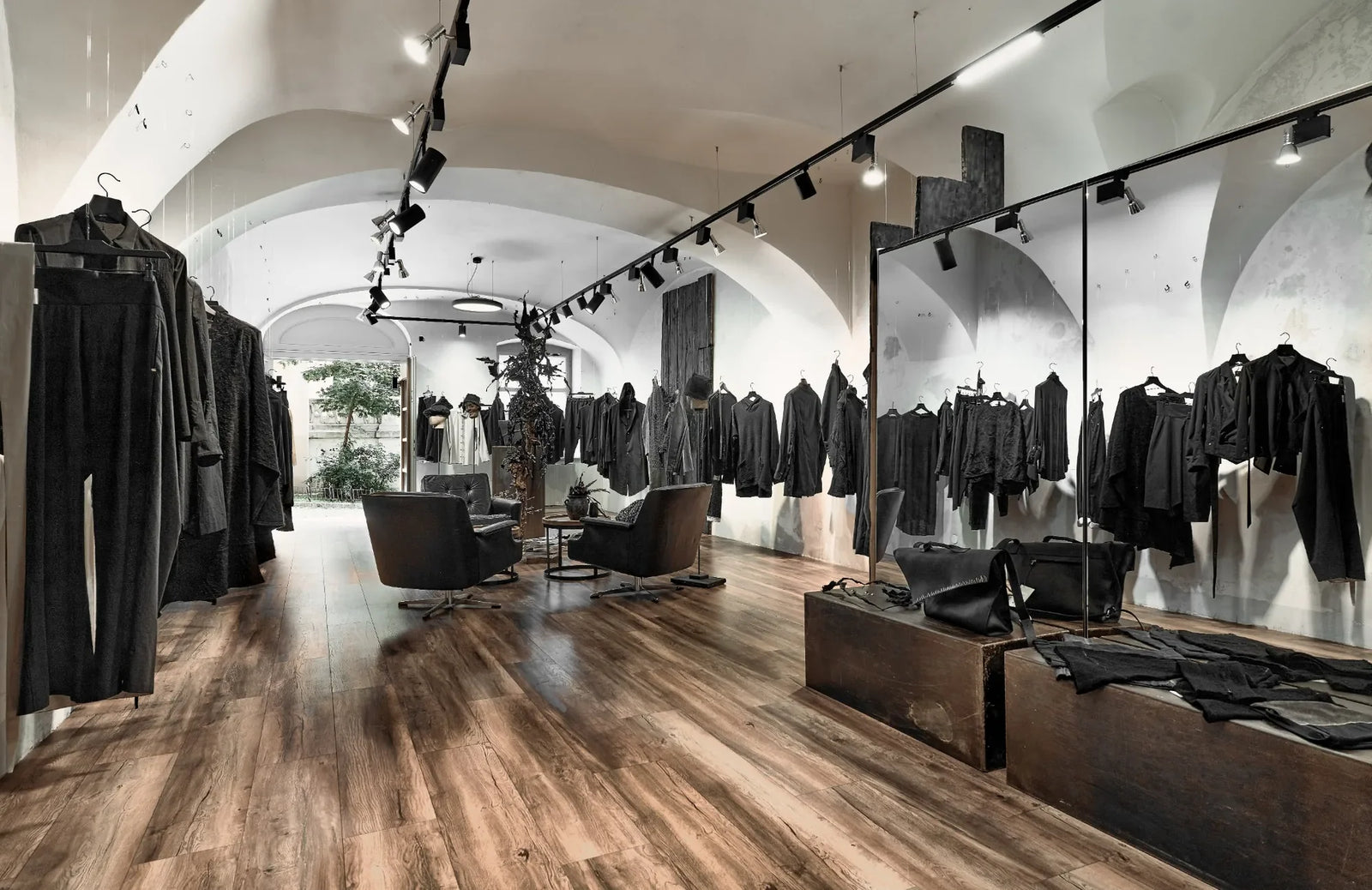 Showroom des eigensinnig Stores in Wien mit schwarzer Avantgarde-Mode, Spiegeln und Sitzbereich