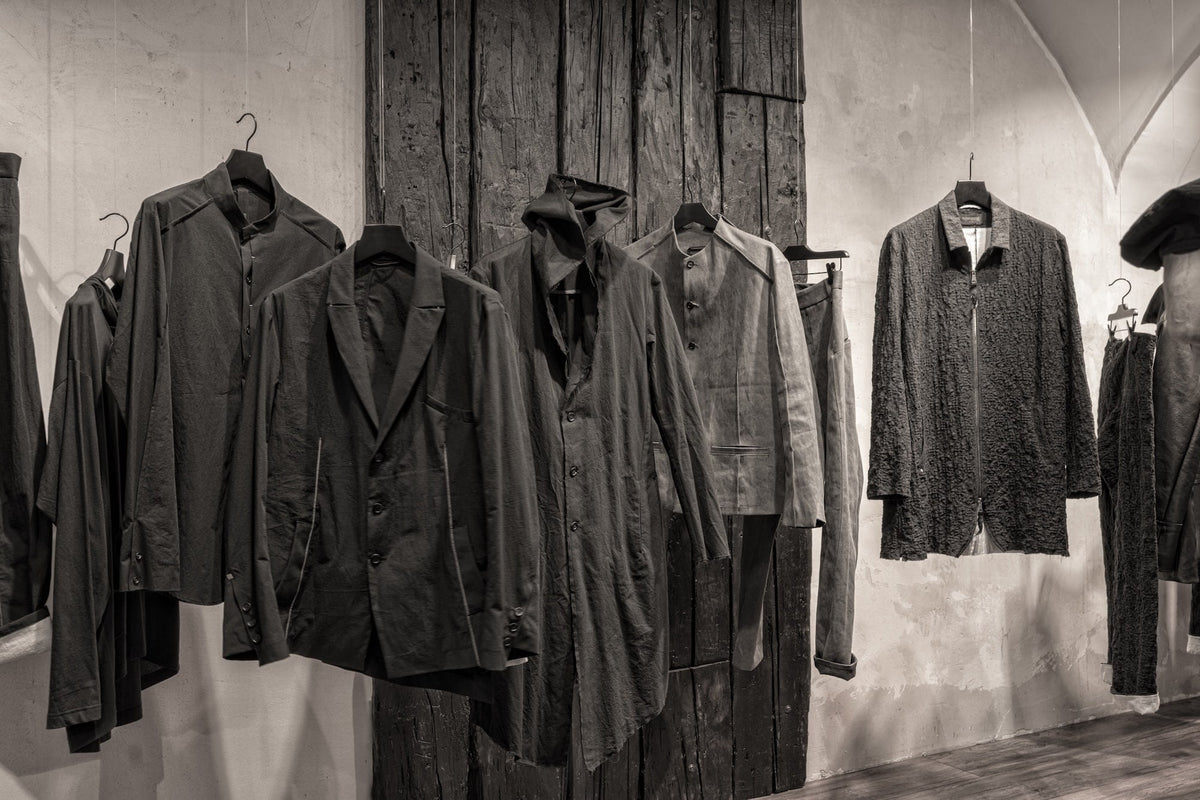 Schwarze Avantgarde-Jacken, Blazer und Mäntel von eigensinnig wien vor einer historischen Holzwand in der Wiener Modegalerie.